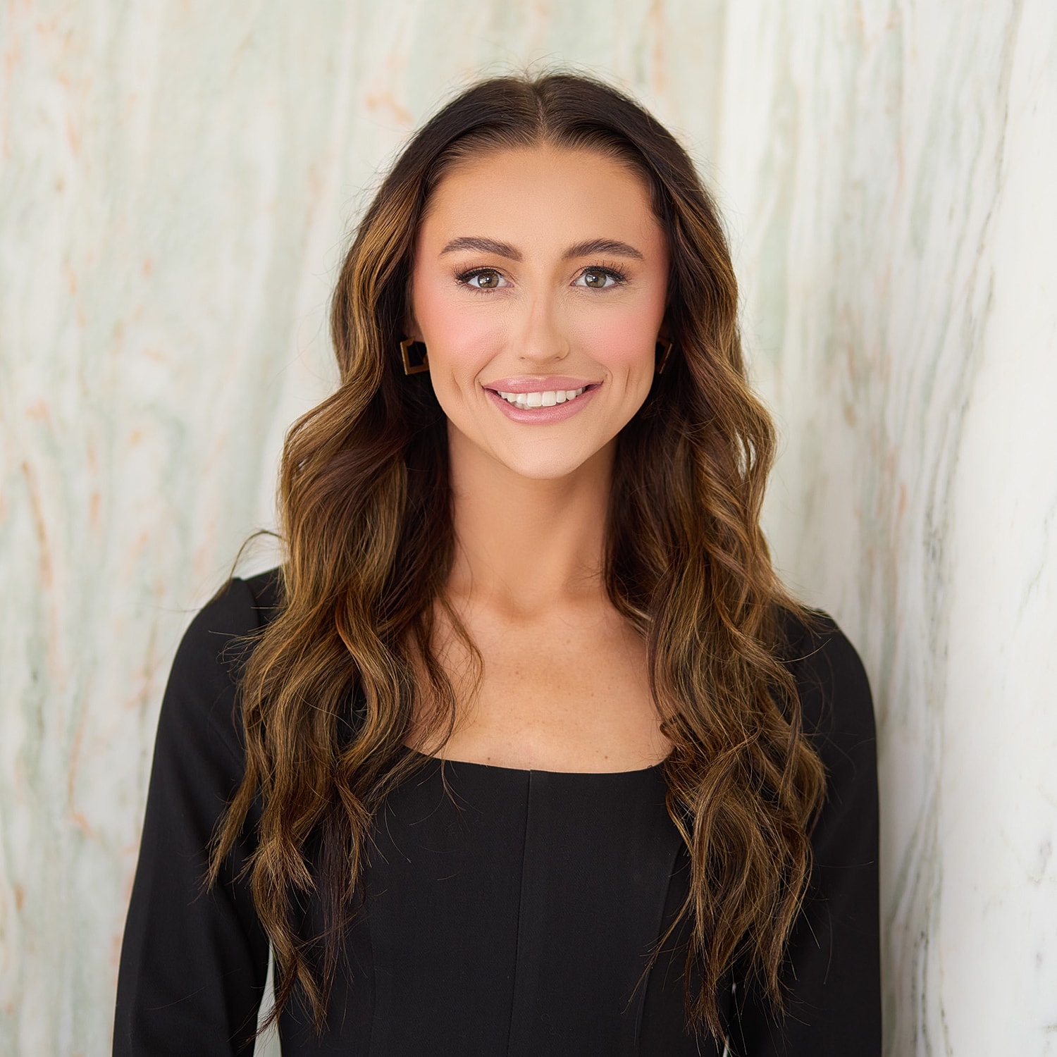 Smiling woman in black attire against white background.