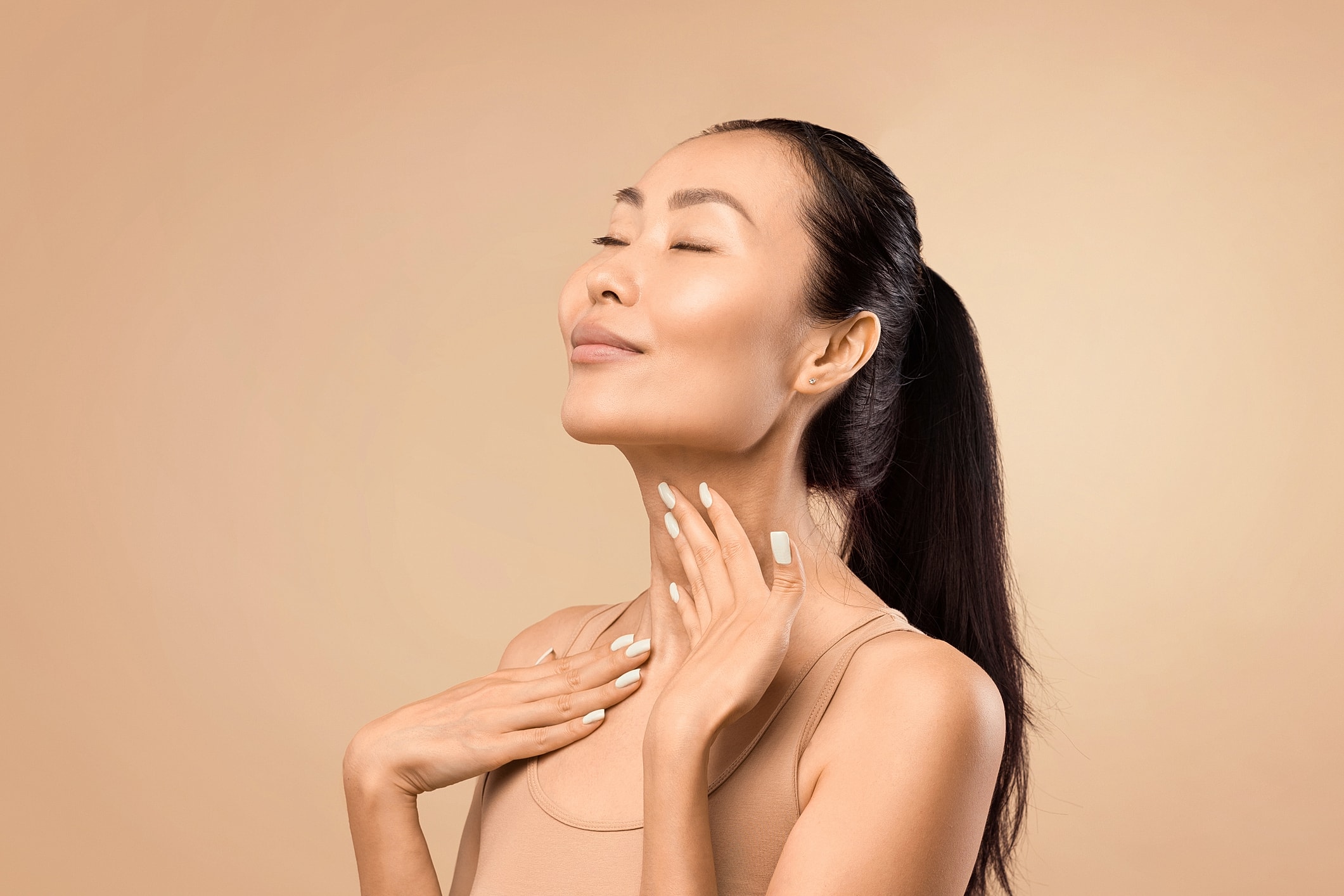 Woman with closed eyes, smiling and touching neck.