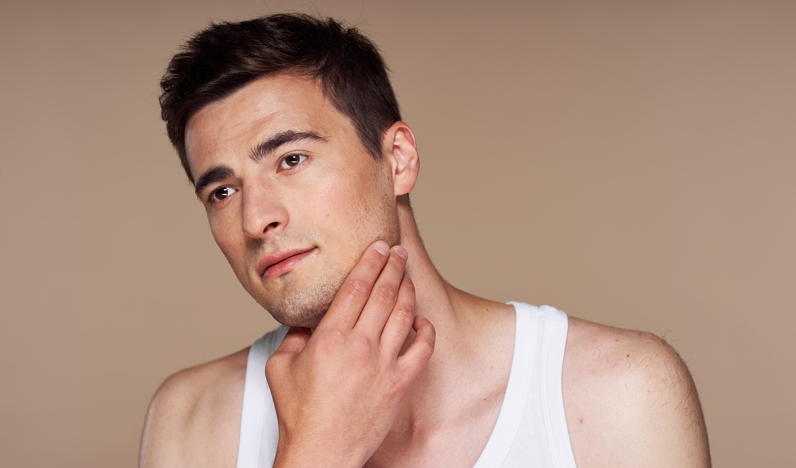 Man touching his jaw, contemplative expression.