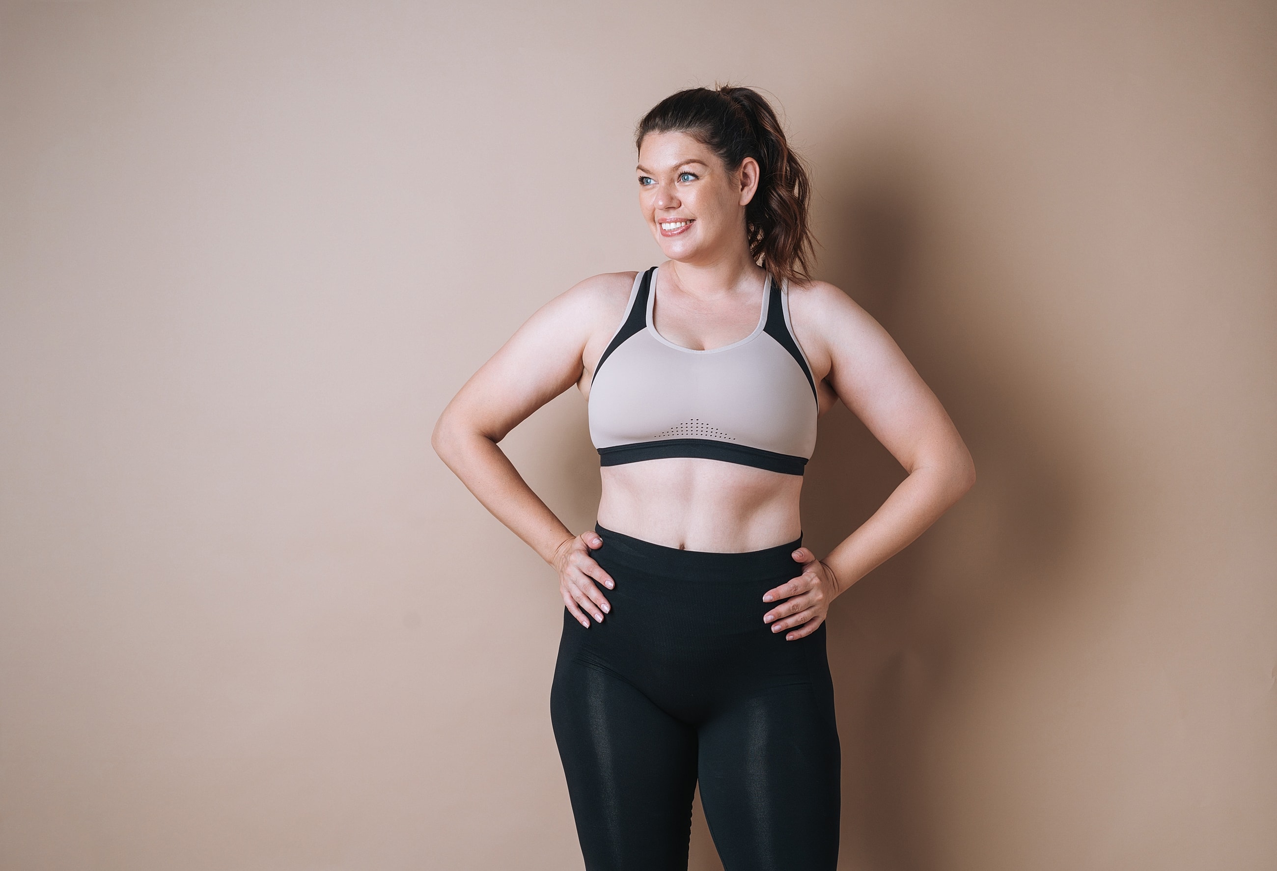 Smiling woman in activewear against a neutral backdrop.